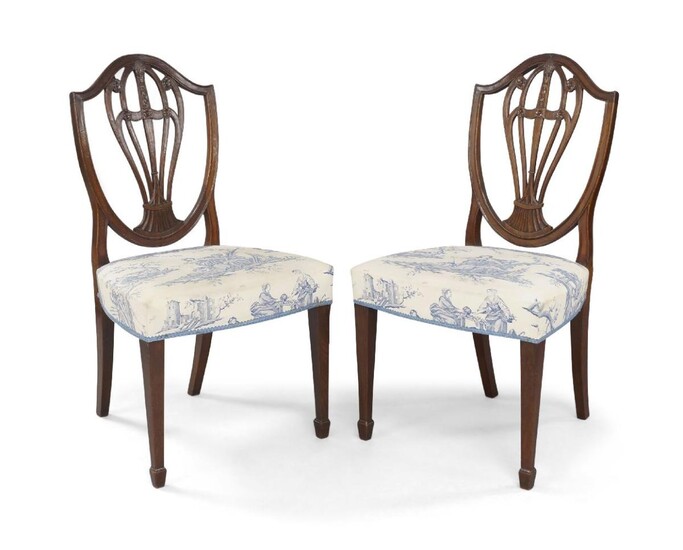 A pair of George III mahogany side chairs, circa 1780, the shield shape back rests with balloon shape fret work, carved with pineapple and floral motifs