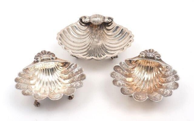 A pair of silver scallop shell dishes, Birmingham, 1968, A Marston & Co., raised on three scroll feet and chased with foliate scroll decoration, 11.1 x 13.5cm together with a larger scallop shell dish, stamped 925, approx. 15cm dia., total weight...