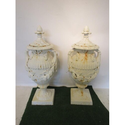 A pair of white painted cast iron garden urns and lids raise...