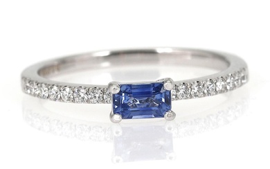 A sapphire and diamond ring set with an emerald-cut sapphire weighing app....