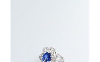 A white gold ring adorned with a large oval sapphire skirted with baguette-cut diamonds.