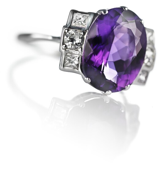 An Art Deco amethyst and diamond ring set with an amethyst weighing app. 5.00 ct. flanked by numerous old and princess-cut diamonds, mounted in 14k white gold.