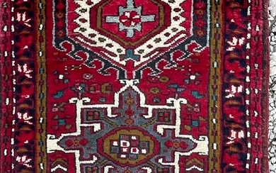 An early 20th century North West Persian Islamic Heriz hand woven floor carpet runner rug having a central panel with alternating stylized foliate patterns in earthy colourways enclosed within a series of graduating outer borders singularly decorated...