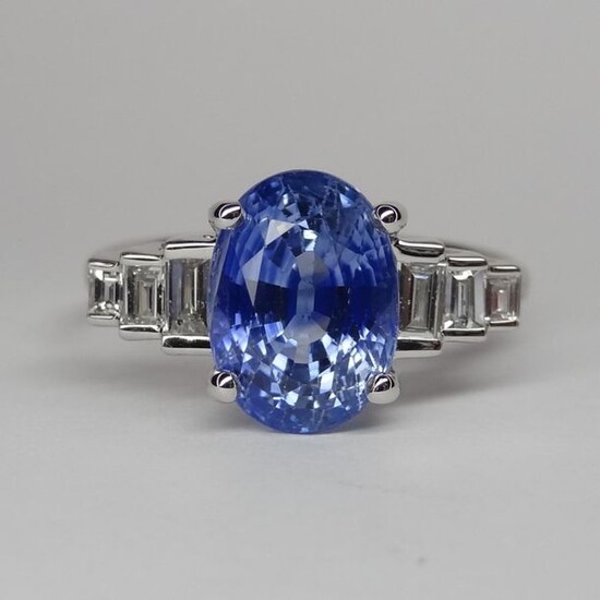 Ring in white gold, 750 MM, set with a 3.50 carat oval Ceylon coloured sapphire, stepped baguette-cut diamonds, size 17 / 10 mm, cut: 54, weight: 3.6gr. rough.