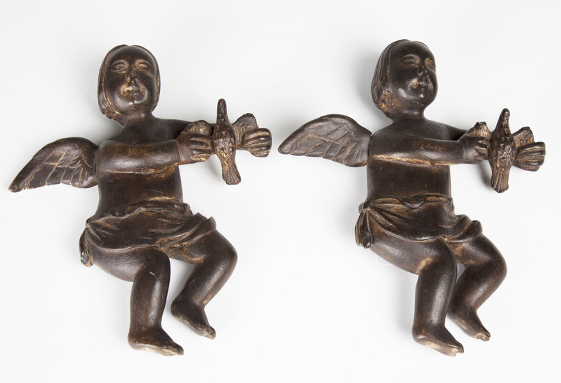 Two carved and stained wooden figures of cherubs, probably 19th century, each holding a bird, height