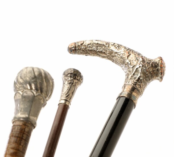 Two early 20th century wood and silvered metal walking sticks, one wrapped in leather. L. 87–91 cm. (3)