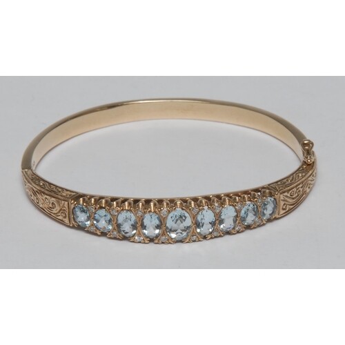 A 15ct gold aquamarine and diamond hinged bangle, the nine g...