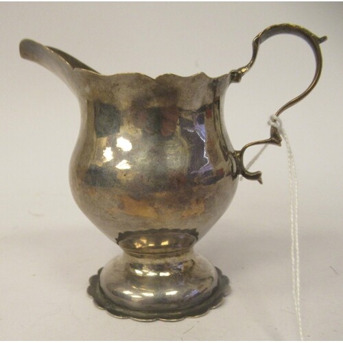 A George III silver cream jug of bulbous form with a decorat...