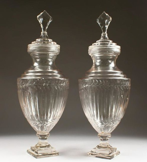 A LARGE PAIR OF CUT GLASS PEDESTAL URNS AND COVERS.