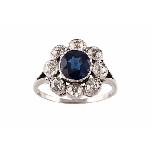 A SAPPHIRE AND DIAMOND CLUSTER RING, the oval sapphire to an...