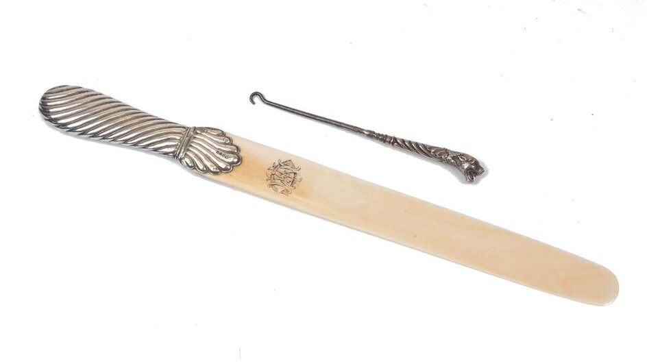 A Victorian silver mounted page turner, London, c.1886, William Comyns, with niello monogrammed ivory blade, together with a button hook, the handle modelled as a lion head set with red paste eyes, marks rubbed, assumed silver (2)