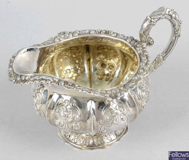 A William IV embossed silver pedestal cream jug.