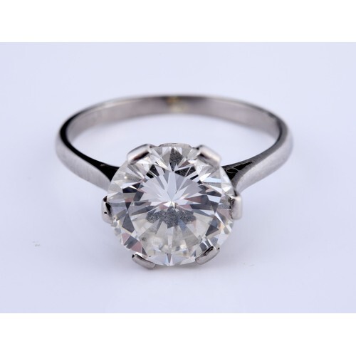 A large and impressive diamond solitaire ring, on white meta...