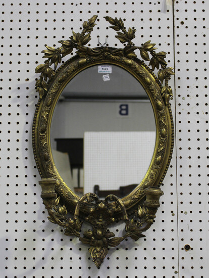 A late Victorian gilt gesso framed oval girandole wall mirror with stiff leaf spray surmount and two