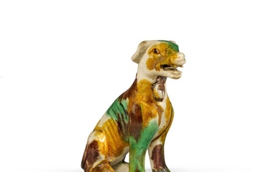 A small 'egg and spinach'-glazed biscuit porcelain figure of a seated hound Qing dynasty, Kangxi/Yongzheng period | 清康熙/雍正 素三彩犬