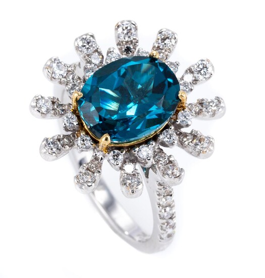 AN 18CT WHITE GOLD TOPAZ AND DIAMOND STARBURST RING; centring on a 2.8ct oval cut London blue topaz to surround and shoulders set wi...