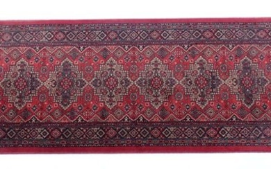 Carpet / Rug : A red ground runner with repeating motifs to centre, bordered by geometric banding.
