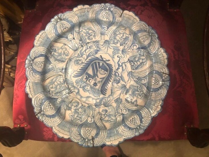 Grand plat en faience de forme polylobée à décor en relief en camaieu de bleu sur fond blanc, orné en son centre d'une armoirie