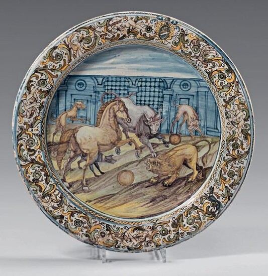 Italian earthenware dish (Castelli, Grüe's workshop) from the middle of the 17th century. With blue, green, ochre and manganese decoration, in the centre of a scene with an animal fight in an architectural landscape, the wing of coat of arms in a...