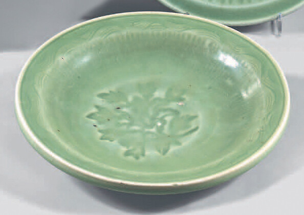 Small porcelain cup of China. Kangxi (1662-1722). Enamelled celadon of circular moulded shape, with engraved decoration in the centre of foliage the gadrooned fall, the wing engraved with waves, small splinters at the heel, galling.