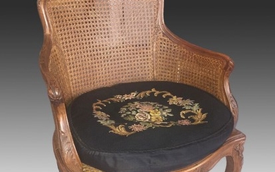 A 20th century French Rococo style walnut polished beech bergere. Loose pillow with embroidery. H. 83 cm.