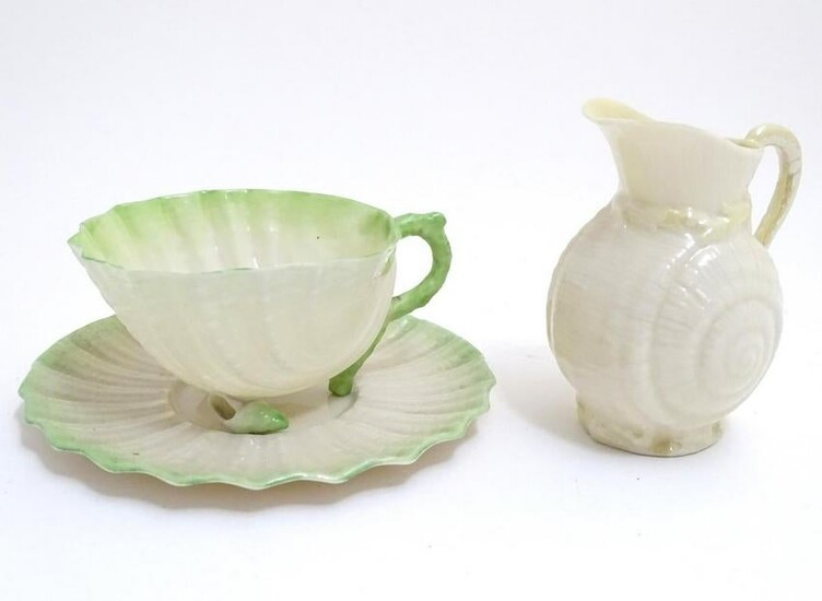 A Belleek tea cup and saucer of shell form with green