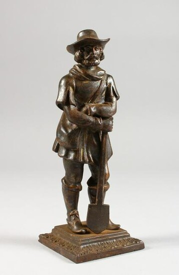 A CAST METAL FIGURE OF A MAN LEANING ON A SPADE.