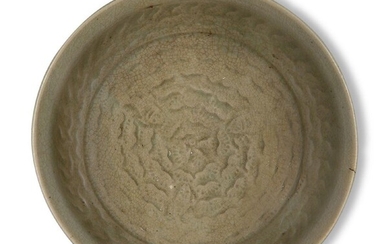 A Chinese Yaozhou celadon carved 'fish' bowl, Song dynasty, on short foot with rounded sides rising to an everted rim, the interior carved with three small fish amongst waves, covered in an allover brownish-green crackle glaze, 12.9cm diameter