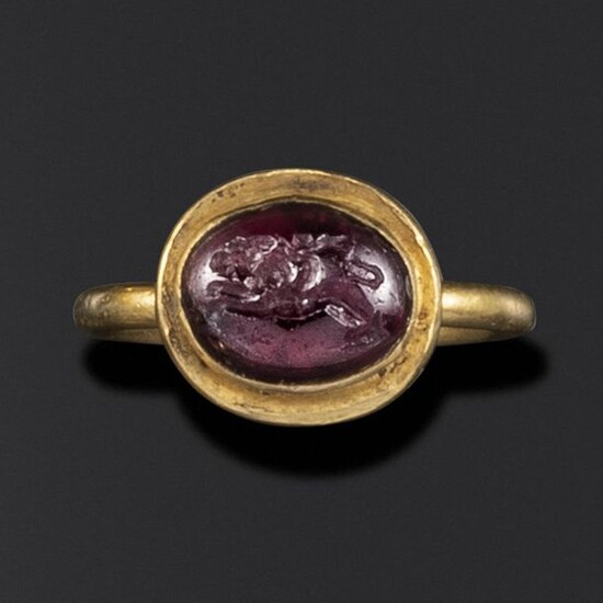 A Hellenistic domed garnet intaglio of Eros riding a lion, c2nd-1st century BC, in a late Roman gold ring, c4th-5th century AD, intaglio 1.1cm high, ring size L
