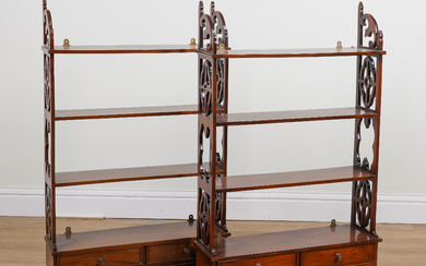 A PAIR OF GEORGE III STYLE MAHOGANY FOUR TIER SHELVES EACH WITH FOUR DRAWER BASE AND FRET CARVED SIDES (2)