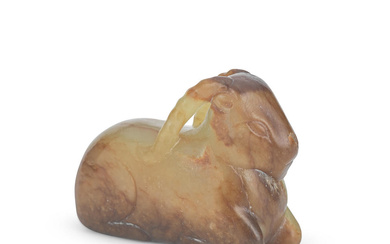 A YELLOW AND RUSSET JADE CARVING OF A RECUMBENT RAM...