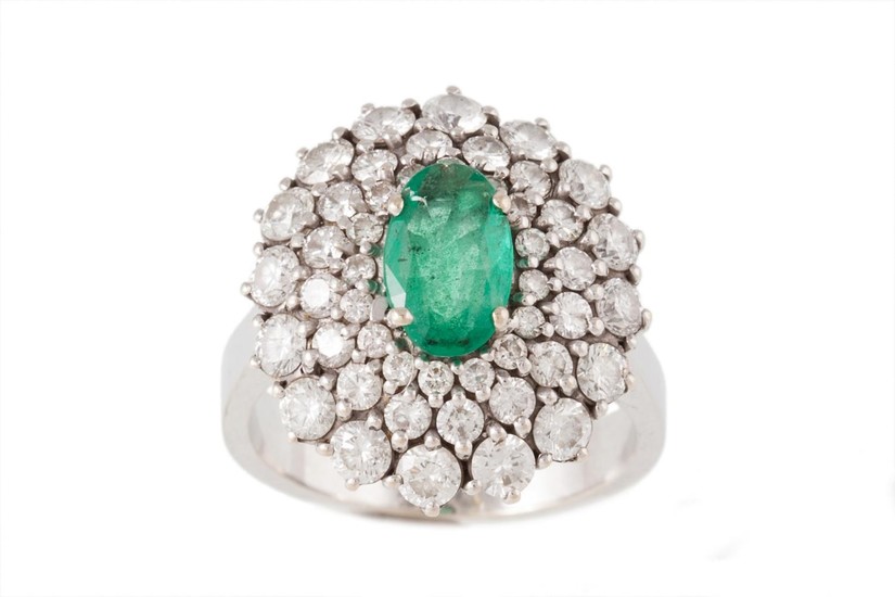 AN EMERALD AND DIAMOND OVAL CLUSTER RING, with emerald of ap...