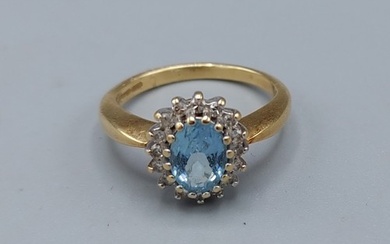 An 18ct gold ring set with a central Aquamarine surrounded b...
