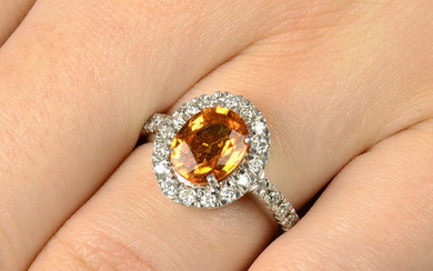 An orange sapphire and diamond cluster ring.