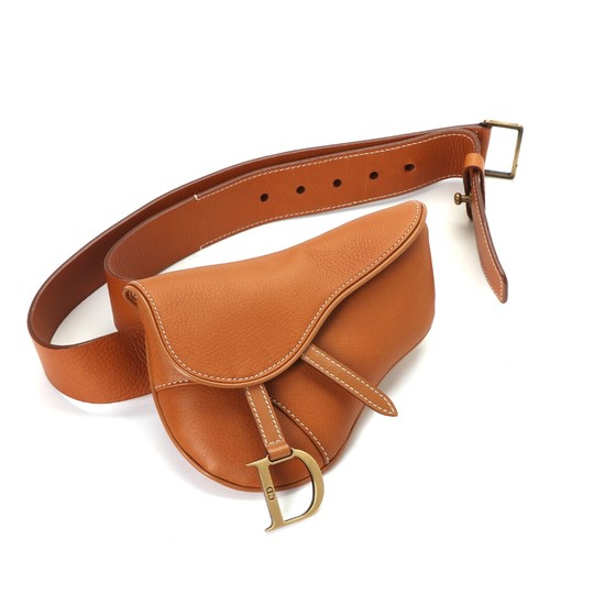 Christian Dior: A “Saddle clutch belt” bag made of light brown leather with golden hardware, a magnetic closure and one compartment.