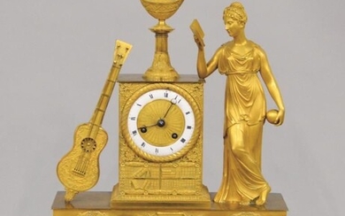 Pendule en bronze doré à décor d'une jeune femme au livre et guitare. XIXe siècle....