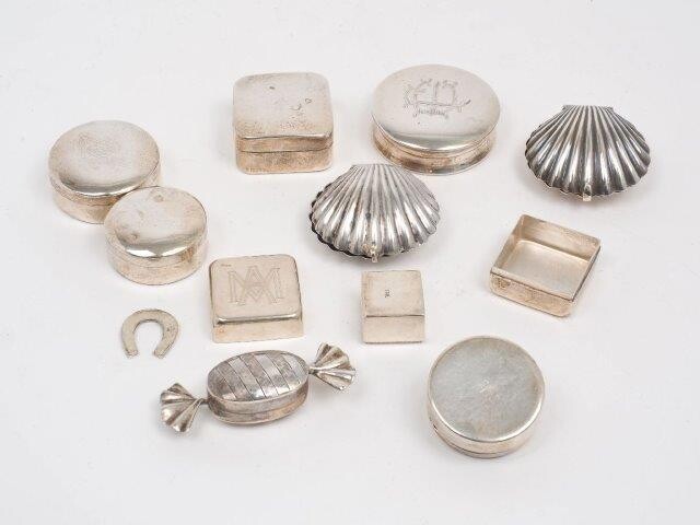 Ten silver and white metal trinket and pill boxes, all stamped 925, the group including one box designed as a wrapped sweet, London, 1999, Ari D Norman, 6.3cm long; a Greek example with applied teddy bear to lid, and two designed as scallop shells...