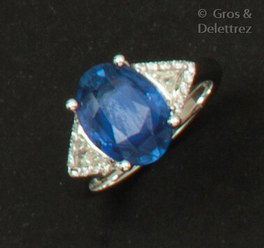 White gold ring set with an oval facetted sapphire set with troika diamonds.
