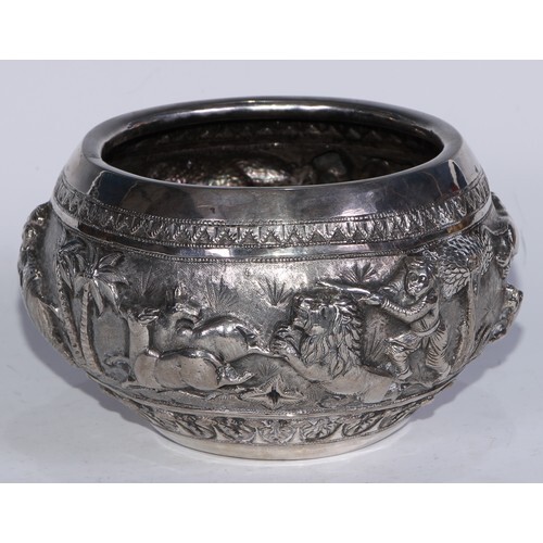 A Burmese silver bowl, chased in bold relief with a hunting ...