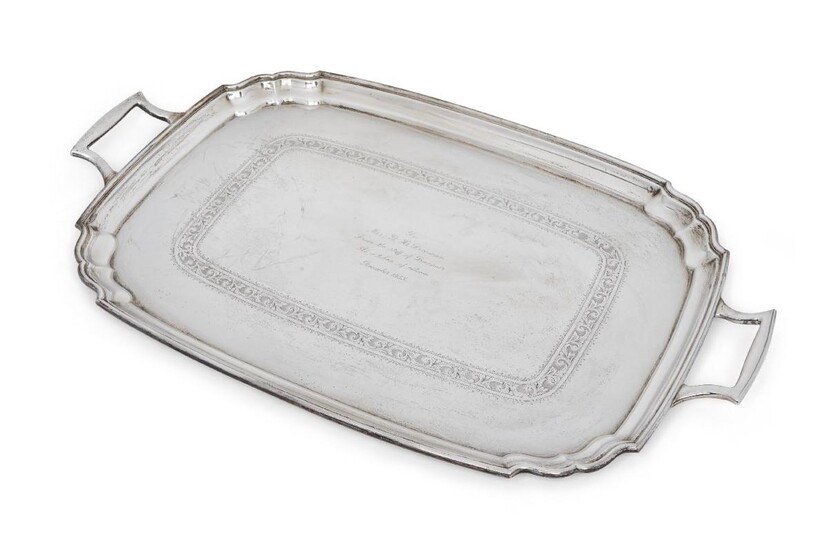 A George V twin handled silver tray, Sheffield, 1934, Frank Cobb & Co., of rectangular form with shaped corners, the base with presentation engraving within foliate engraved band, 40.5 x 65.5cm (inc. handles), approx. weight 99oz