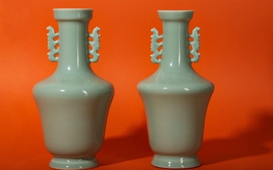 A PAIR OF CHINESE PALE CELADON-GLAZED VASES. Each with a tapered body and a rounded shoulder rising to a cylindrical neck with two stylised dragon handles, all coated with an even pale celadon glaze and with six character Yongzheng marks to the...