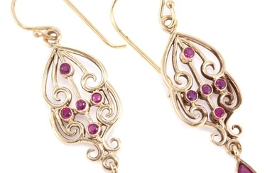 A PAIR OF NOUVEAU STYLE RUBY EARRINGS; scrolling 9ct gold wirework frames set with round cut rubies to pear cut ruby drops on shephe...