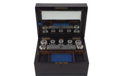 A Victorian travelling vanity box, containing various silver and white metal mounted glass vanity jars and bottles, London 1859 and 1861, the bottle lids unmarked, some vanity accessories deficient, the ebony box designed with internal mirror and...