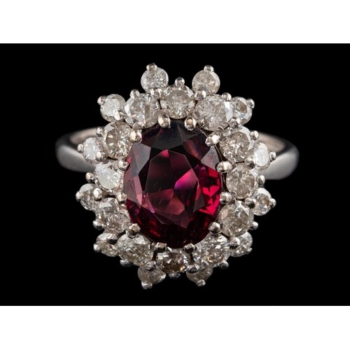 A garnet and diamond cluster ring:, the central oval cut gar...