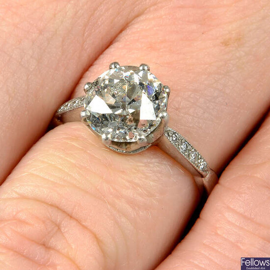 A platinum old-cut diamond single-stone ring, with brilliant-cut diamond line shoulders.