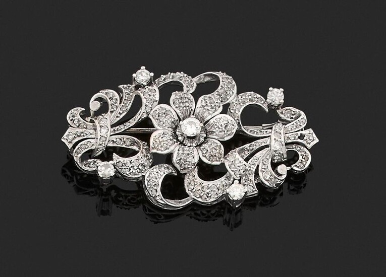 BROCHURE in 750 thousandths openwork white gold decorated with clasps and a flower in the centre, entirely set with rose-cut, antique cut and brilliant-cut diamonds, some of them larger. Length. 5.2 cm. Gross weight: 15 g. (missing a diamond). Brooch...