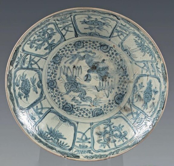 Chinese glazed stoneware dish (Swatow). 17th century. With blue-white decoration, in the center of two dragons in a medallion, the wing and the fall of flowers and trees in interspersed reserves, braid on the edge, floral motifs on the reverse, small...