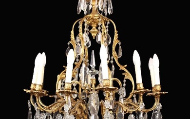Lustre à douze branches en métal doré de style Louis XV. Les branches à enroulement...