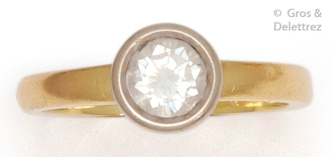 Ring " Solitaire " in yellow gold, set with a brilliant-cut diamond in a closed setting in white gold. Weight of diamant : 0.85 carat approximately. Turn of doigt : 55. P. Brut : 5 g.