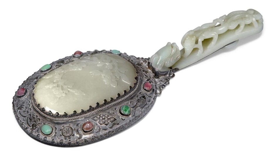 A Chinese greenish-white jade plaque and a pale green jade belt hook, 18th century, mounted to form a hand mirror, the plaque carved in low relief with flowering peony blossoms amongst leafy branches, 10.5cm x 7cm, the belt hook carved with...